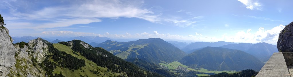 Wendelstein - Panoramaansicht des Wendelsteins mit grünen Hügeln und Bergen im Hintergrund unter blauem Himmel.