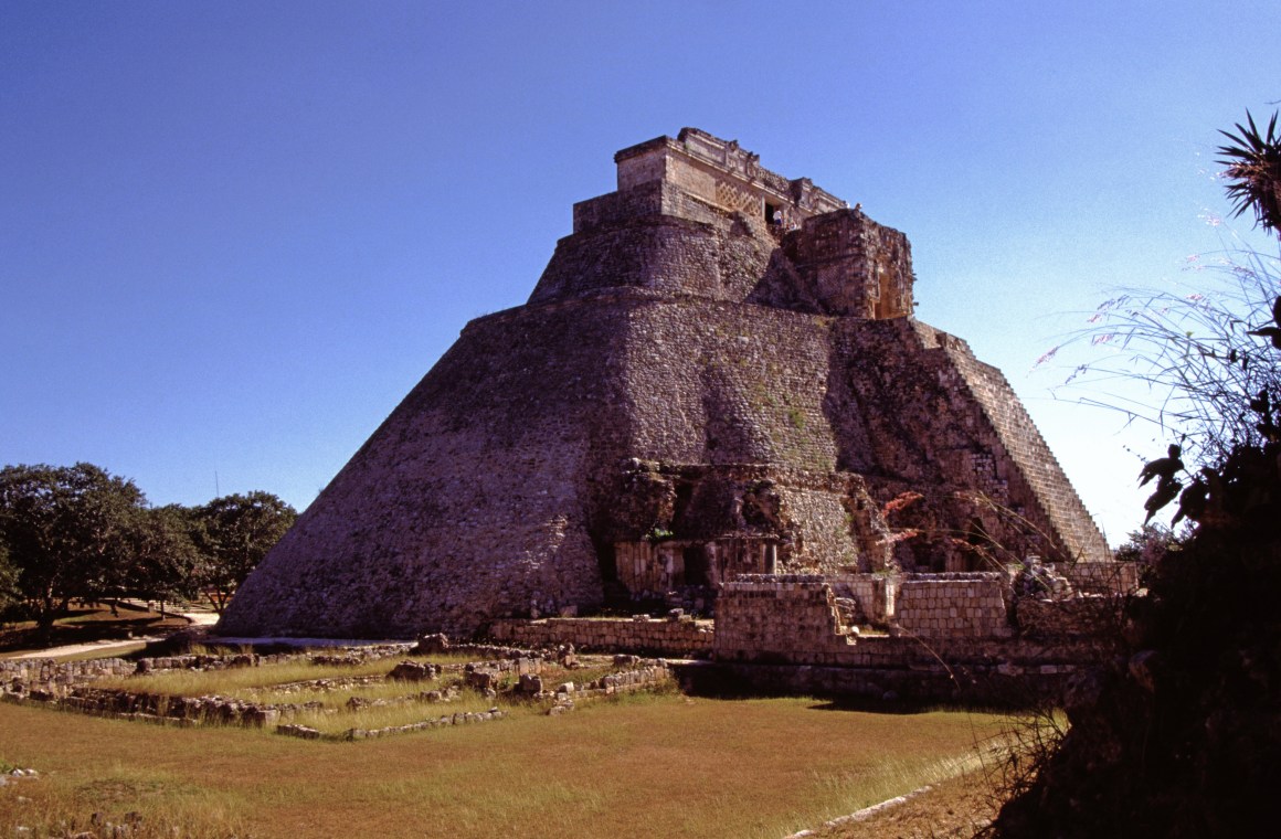 Mexiko Uxmal - Eine ovalförmige, sehr hohe Pyramide. Im Vordergrund Rasen und weitere Ausgrabungsflächen