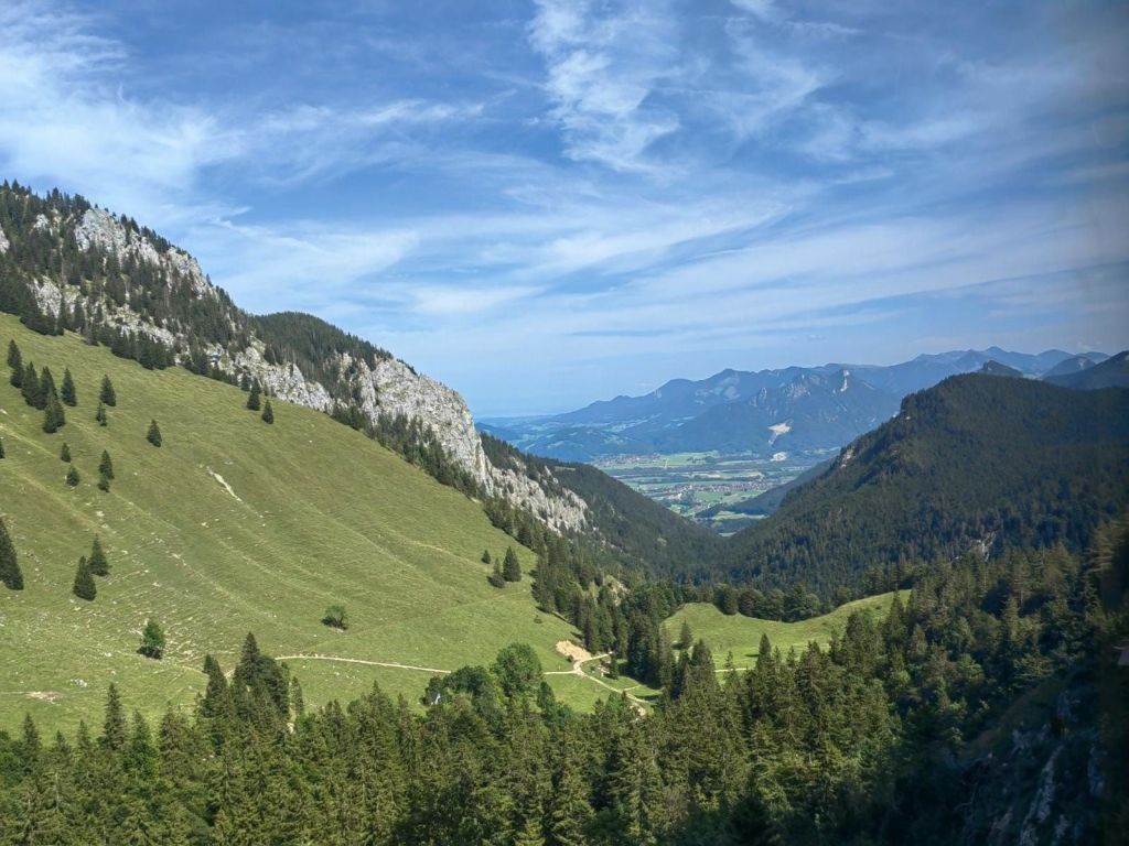 Wendelstein - Panoramaansicht des Wendelsteingebirges mit steilen Hängen und bewaldeten Flächen unter blauem Himmel.